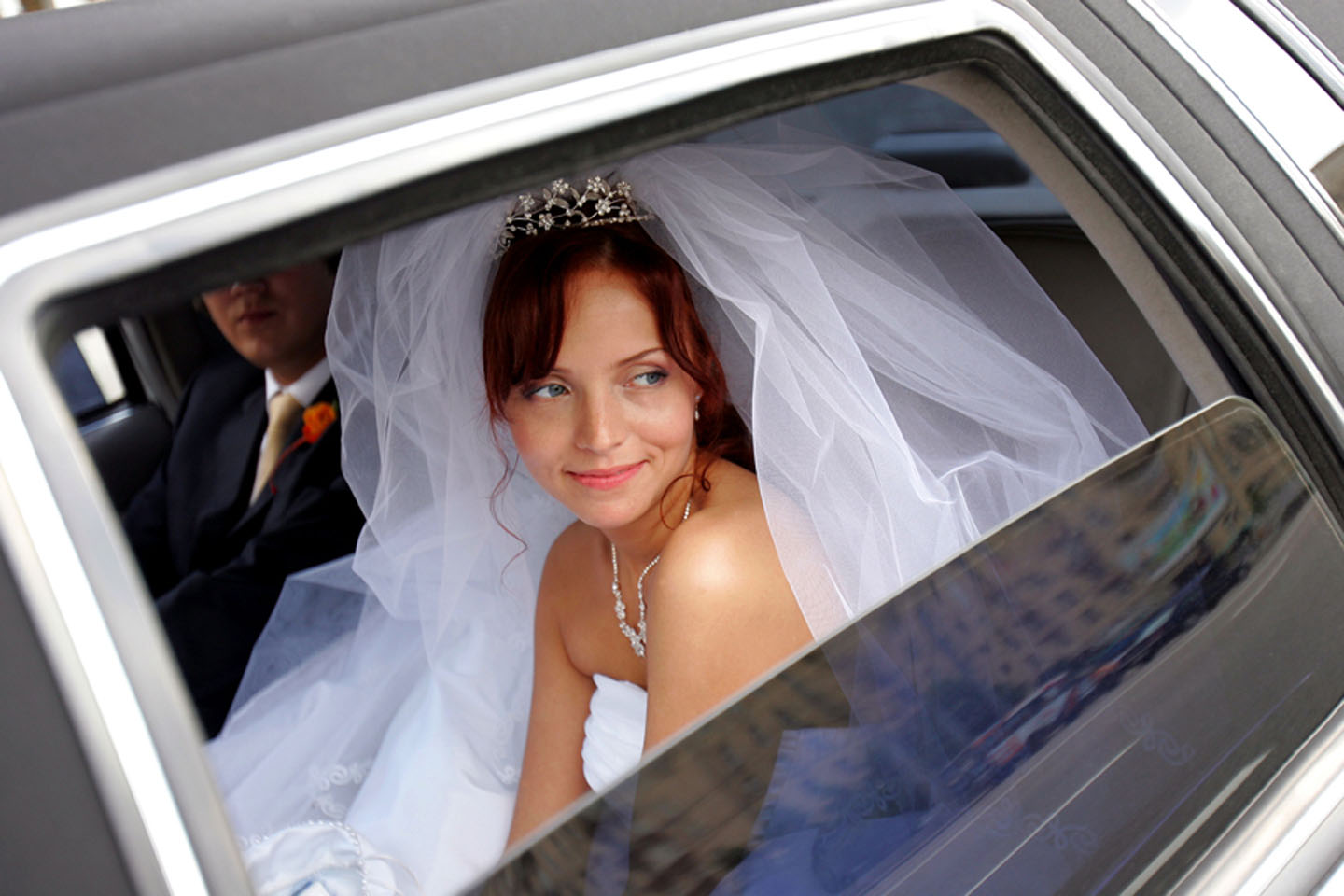A bride looking out a window of a limousine