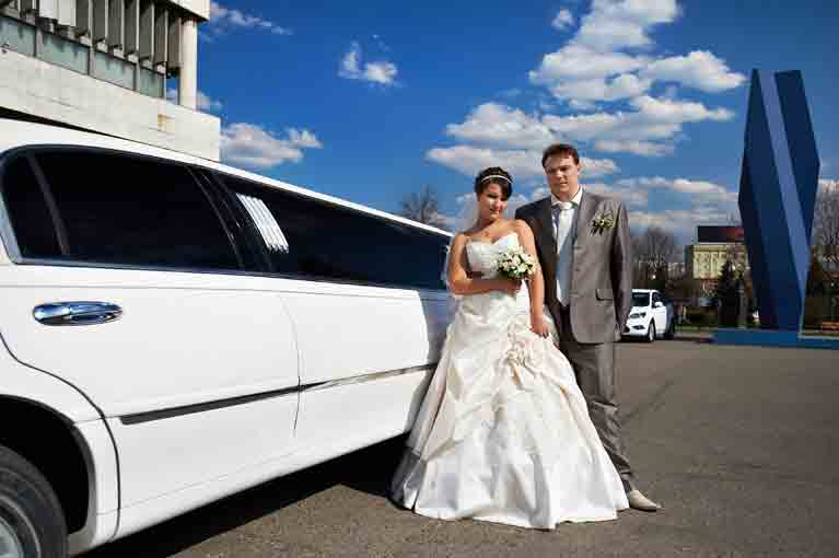 A bride and groom outside of a limousine